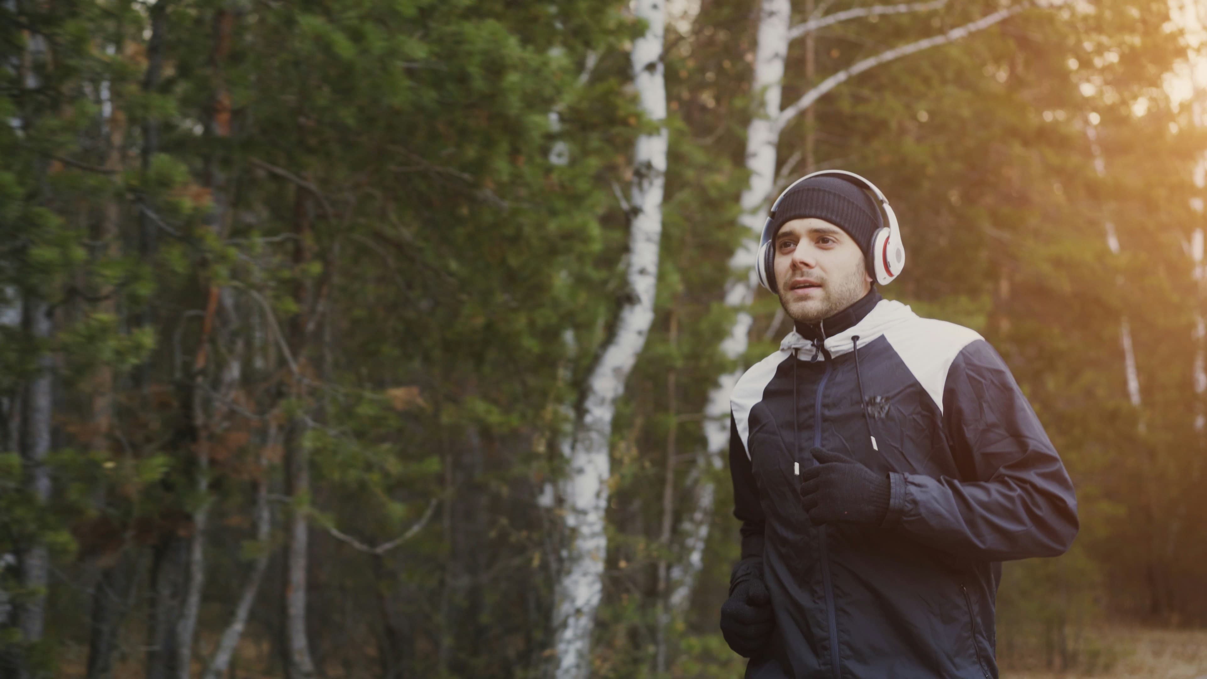 Un coureur en forêt, casque sur les oreilles, un matin d'automne